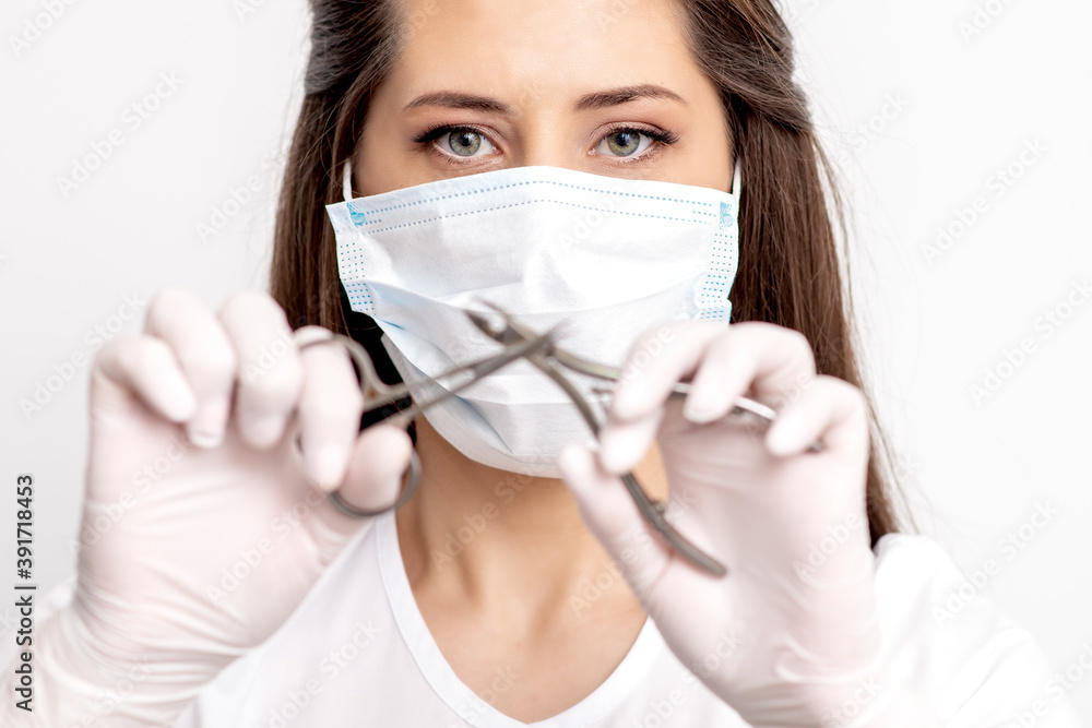 Portrait of manicure master with white protective mask holding manicure tools on white background Portrait of manicure master with white protective mask holding manicure tools on white background