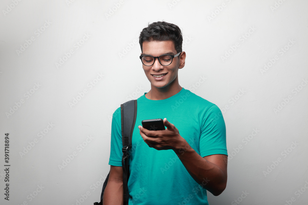 Happy young man of Indian origin looking at his mobile phone Happy young man of Indian origin looking at his mobile phone