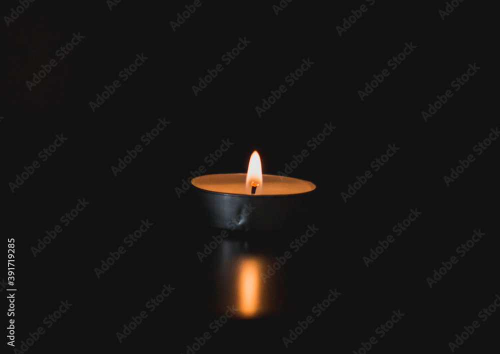 Vela encendida en la oscuridad iluminando la mesa con su reflejo Vela encendida en la oscuridad iluminando la mesa con su reflejo