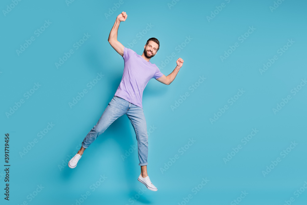 Full length body size photo of young student jumping showing muscles biceps triceps smiling isolated on vivid blue color background Full length body size photo of young student jumping showing muscles biceps triceps smiling isolated on vivid blue color background