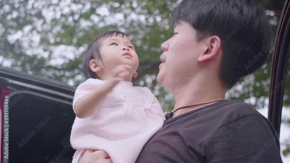 Asian young adult father holding adorable cute baby girl daughter small kid standing next to the vehicle under trees outdoor shot. Asian female infant kiss daddy cheek, Family member Happiness bonding Asian young adult father holding adorable cute baby girl daughter small kid standing next to the vehicle under trees outdoor shot. Asian female infant kiss daddy cheek, Family member Happiness bonding
