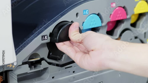 Close-up of replacing a black toner cartridge for color laser printer, male hand pulls on a cartridge