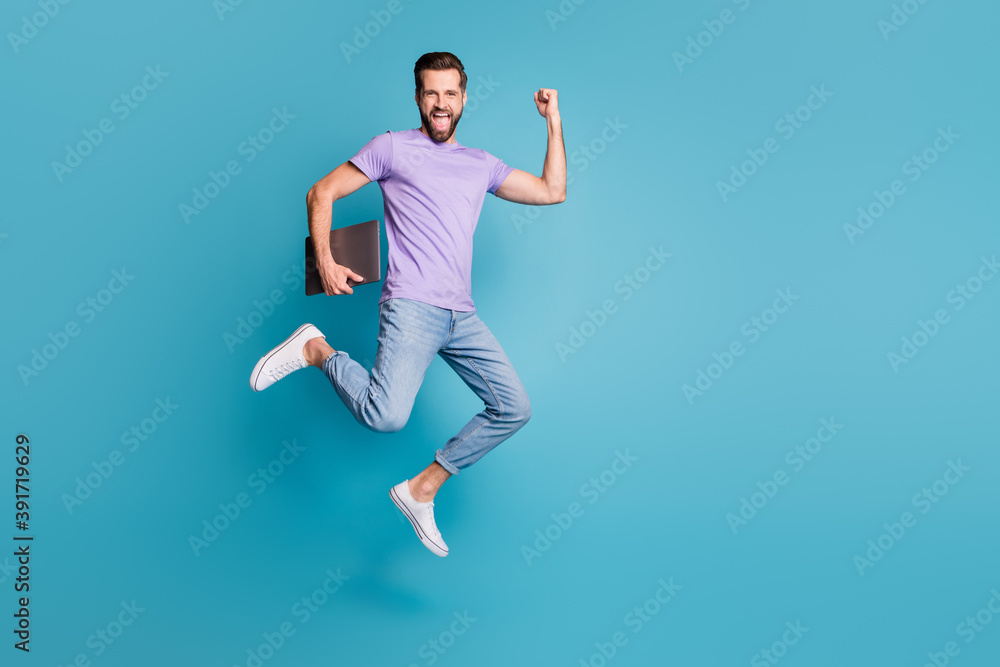 Full length body size photo of jumping high businessman with computer gesturing like winner smiling isolated on vivid blue color background