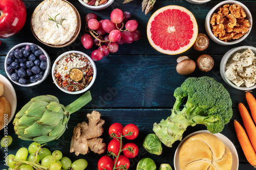 Vegetarian food background design with copy space  a flatlay  shot from above. Fruit and vegetables  cheese  nuts  rice on a dark blue wooden background