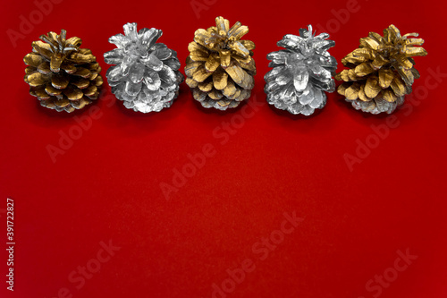 New year 2021. Pine-tree cones golden and silver colors above red Christmas background. 