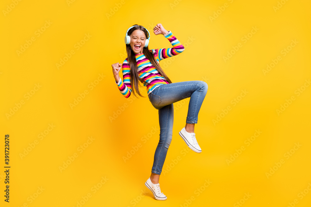 Full length body size photo of careless cheerful girl with earphones dancing gesturing like winner isolated bright yellow color background