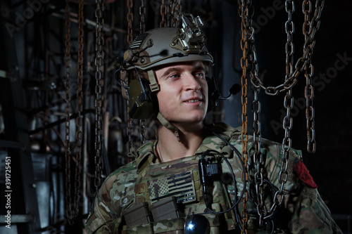 Portrait of an American soldier in camouflage uniform against an industrial background.
