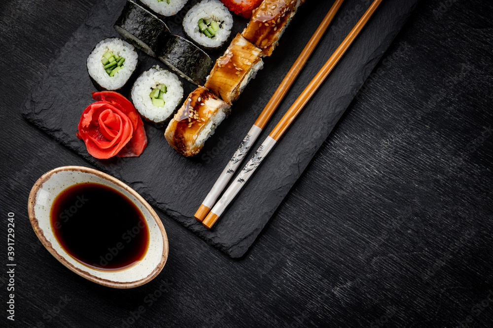 Japanese rolls on black slate board and black background top view, close-up, free space for text Japanese rolls on black slate board and black background top view, close-up, free space for text