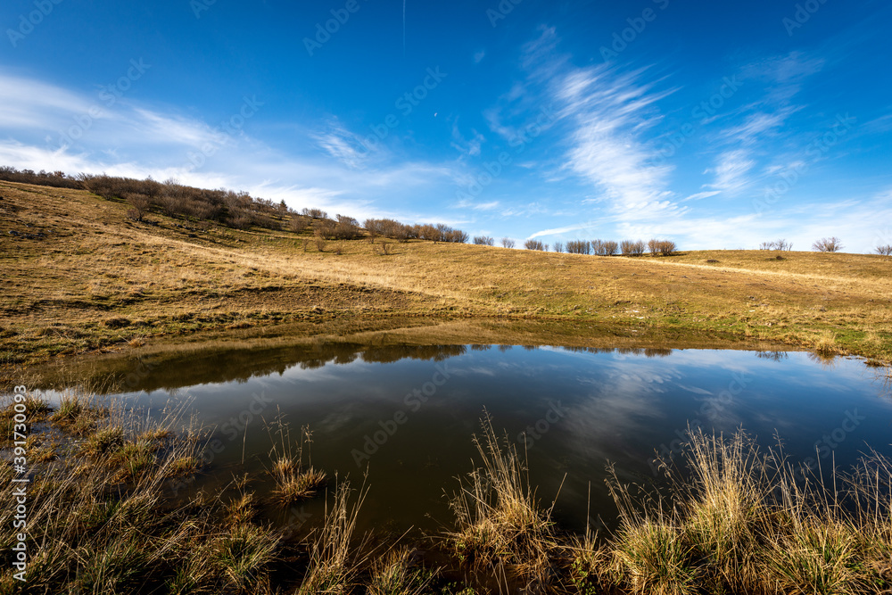 Fototapeta premium Small lake for cows on the Lessinia Plateau Regional Natural Park, Corno d'Aquilio mountain. Verona Province, Veneto, Italy, Europe.