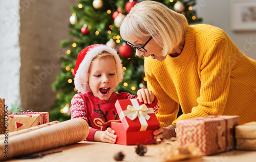 Surprised child getting present from grandmother at Christmas.