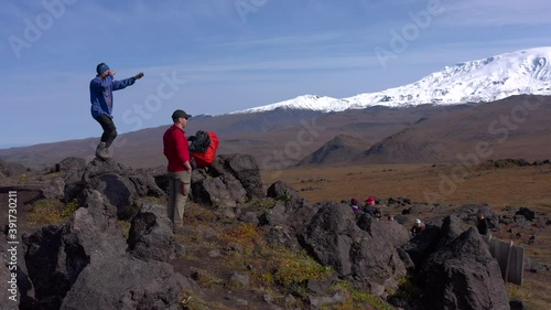 A group of tourists against the backdrop of the amazing volcanoes of Kamchatka. Volcano Plosky Tolbachik. Trekking in the Klyuchevskoy volcano park. Travel to the Kamchatka Peninsula. photo