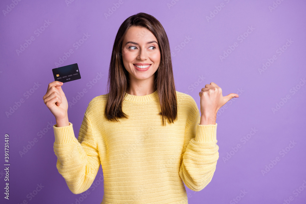 Photo portrait of beautiful girl keeping bank plastic card showing on empty space smiling looking at side isolated on bright purple color background Photo portrait of beautiful girl keeping bank plastic card showing on empty space smiling looking at side isolated on bright purple color background