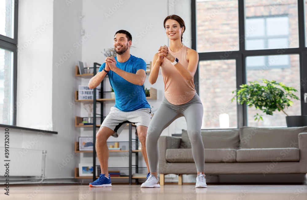 Obraz premium sport, fitness, lifestyle and people concept - smiling man and woman exercising and doing squats at home