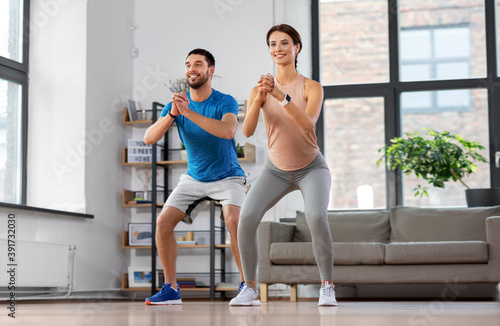 sport  fitness  lifestyle and people concept - smiling man and woman exercising and doing squats at home