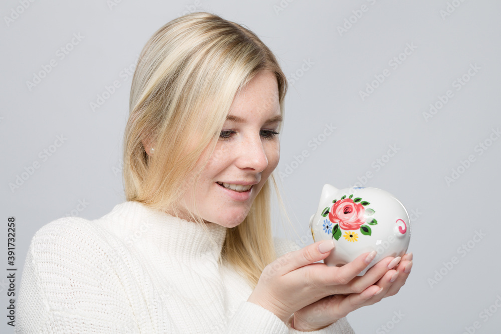 Young happy woman with a piggy bank / porcelain bank in her hand Young happy woman with a piggy bank / porcelain bank in her hand