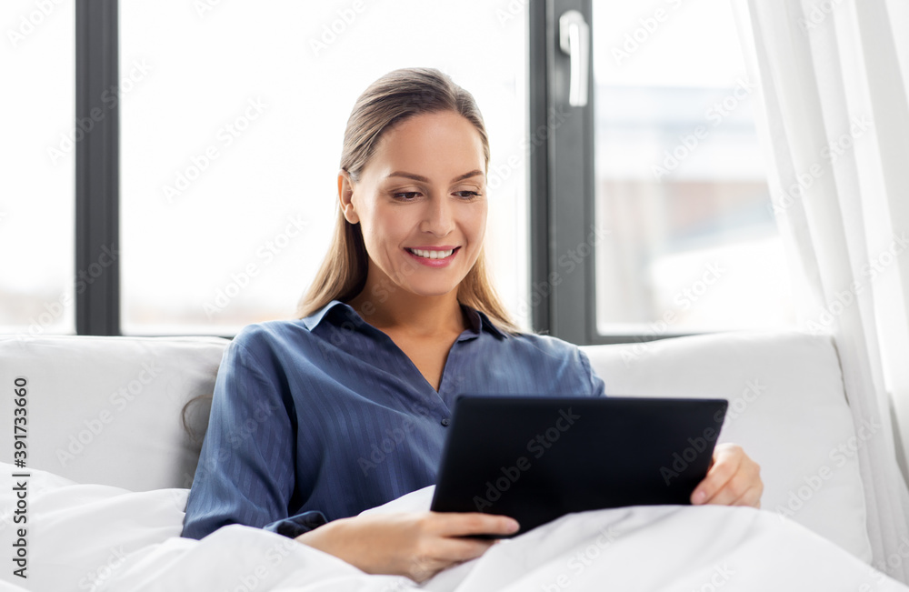 technology, internet and people concept - young woman with tablet pc computer in bed at home bedroom technology, internet and people concept - young woman with tablet pc computer in bed at home bedroom