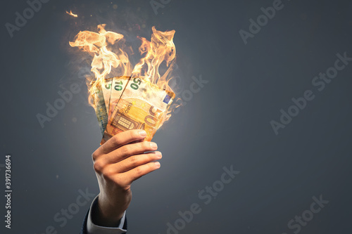 Φωτογραφία Hand holding burning Euro banknotes