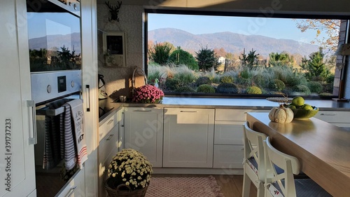 Piękna duża biała kuchnia z oknem panoramicznym, i pięknym widokiem, wyspa w kuchni