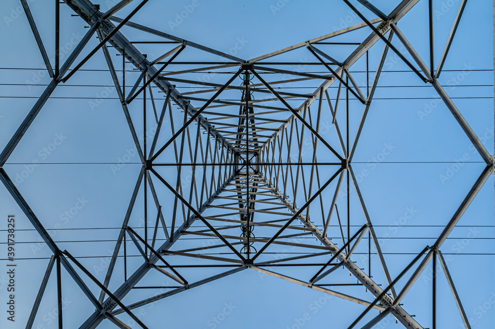 Bottom view of a Transmission tower with a blue sky. Square diagonals from the steel construction and the straight lines from the electrical cables. Bottom view of a Transmission tower with a blue sky. Square diagonals from the steel construction and the straight lines from the electrical cables.