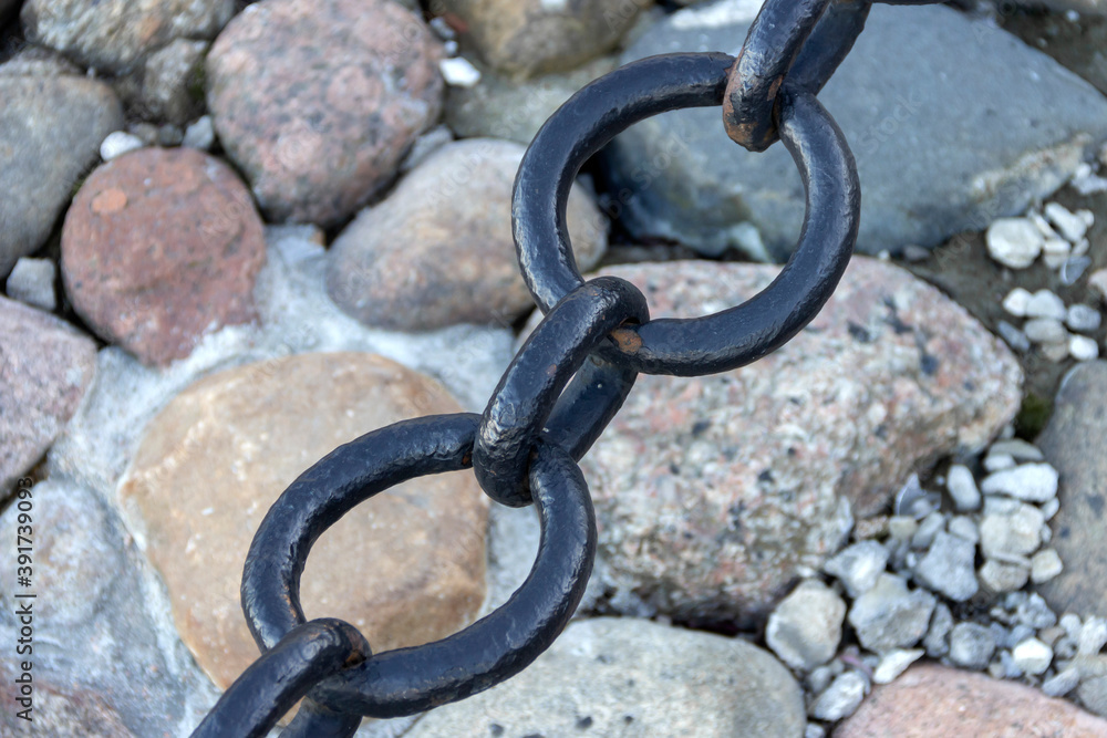 Old forged rusty chain with peeling paint on the background of paving stones. Old forged rusty chain with peeling paint on the background of paving stones.