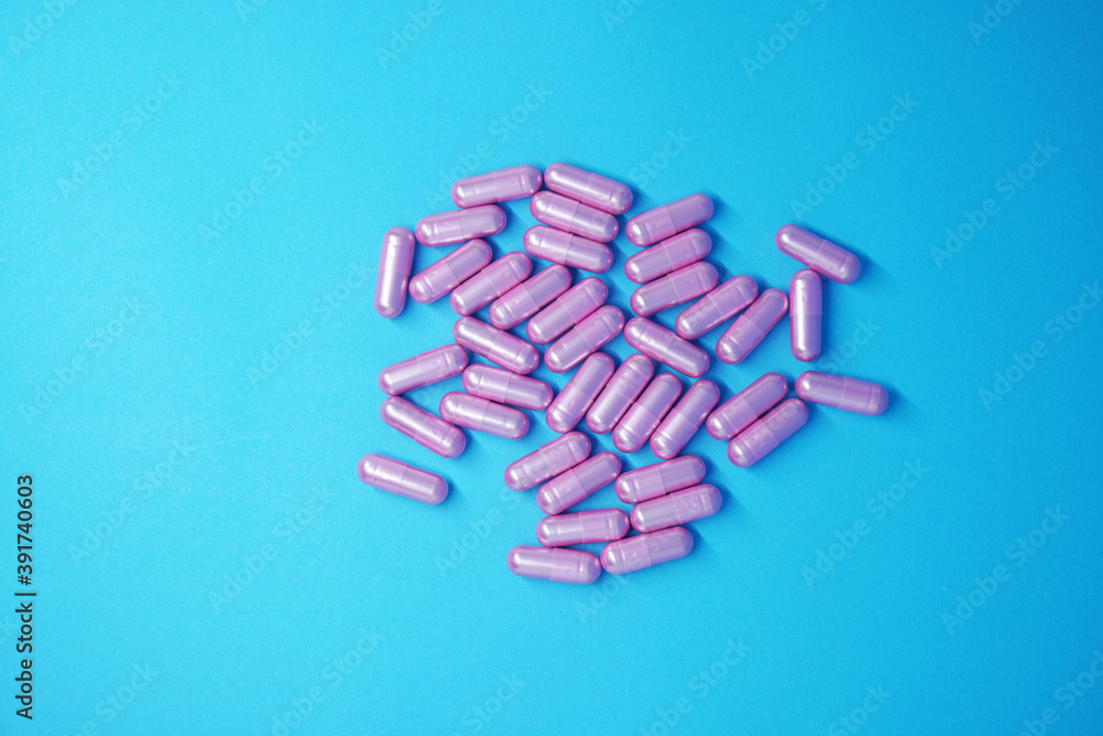 Pink Tablets drug with white bottle of medicine isolated blue background - medical and healthcare concept Pink Tablets drug with white bottle of medicine isolated blue background - medical and healthcare concept