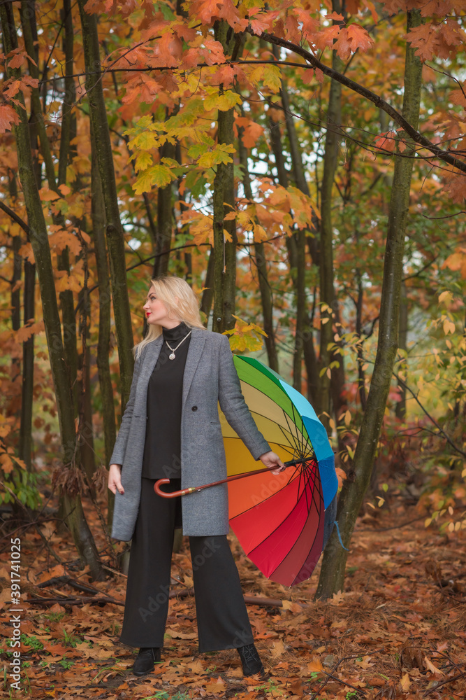 Blonde nice woman at autumn coat and colorful umbrella at park. Pretty plus size European lady Blonde nice woman at autumn coat and colorful umbrella at park. Pretty plus size European lady