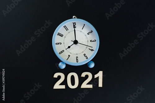 Block letters in 2021 and an alarm clock on black background  photo