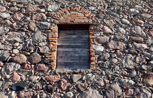 Stone wall background with window opening  boarded up  close-up  side view