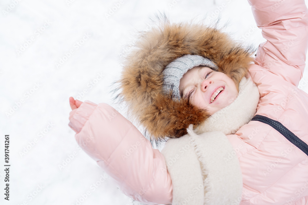 Fototapeta premium Little girl in a fur-trimmed hat laughs while sledding in winter