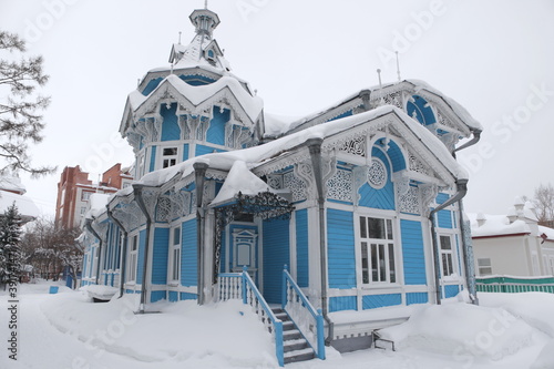 Vintage wooden Russian-German house with ornamental frames in Tomsk city, Russia. Russian folk style in architecture. Tomsk landmark, Tomsk monument, cityscape, view. Snow winter, cold season. Siberia