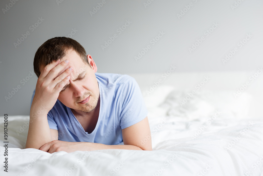 insomnia, depression and headache concept - tired man lying on bed at home
