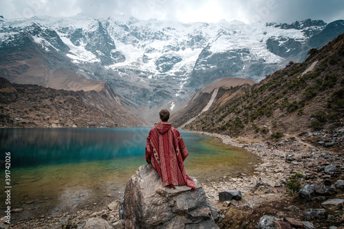 A young man with a poncho on vacation in Laguna Humantay, Peru