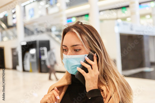 Frau mit Maske wegen Covid-19 telefoniert mit Smartphone