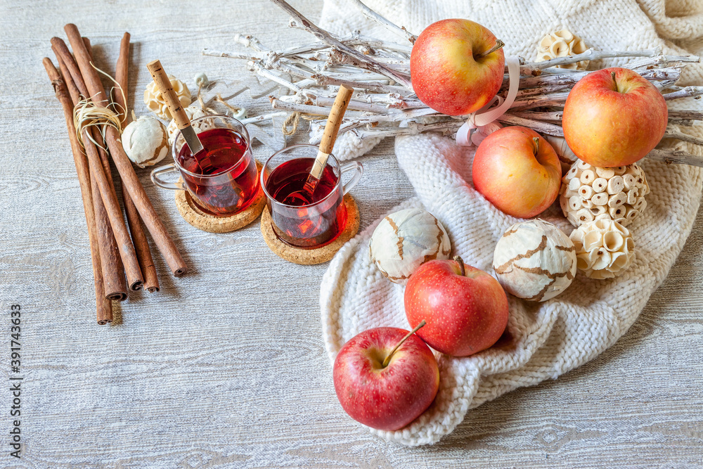 two cups of hot mulled wine with cinnamon red apples and white blanket