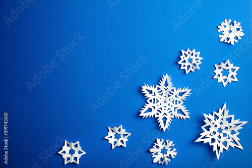 Composition with white paper snowflakes on blue background