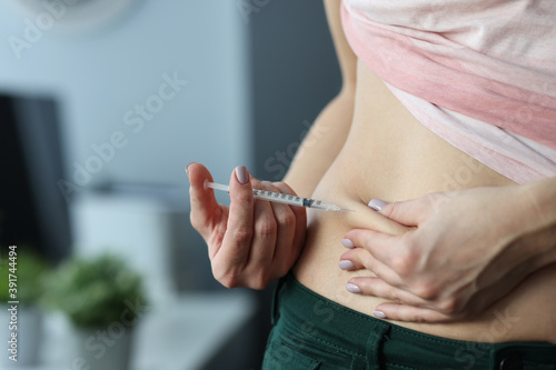 Woman making skin fold on stomach and injecting medicine from syringe at home. Continuous administration of insulin in treatment of type 2 diabetes mellitus concept photo