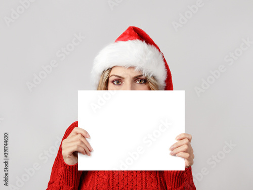 Young woman in santa hat covering her face with blank white paper © katrinshine
