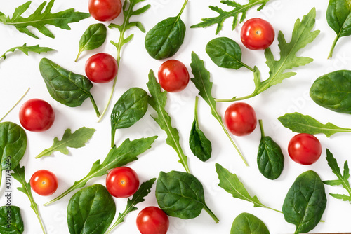 Arugula leaves, spinach and cherry tomatoes on a white background top view. Healthy diet food background. Salad ingredients flat lay.