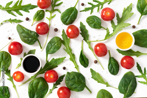 Arugula leaves, spinach and cherry tomatoes on a white background top view. Healthy diet food background. Salad ingredients flat lay.