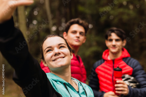 Young woman taking a self-portrait with her friends - Group of friends posing for a selfie in the forest.