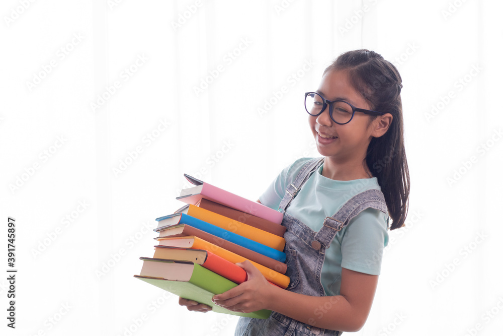 Adorable Asian smart girl in casual jean hold stack of books, adorable intelligent school girl primary looking her many book with happy, girl study at home social distance back to school concept Adorable Asian smart girl in casual jean hold stack of books, adorable intelligent school girl primary looking her many book with happy, girl study at home social distance back to school concept