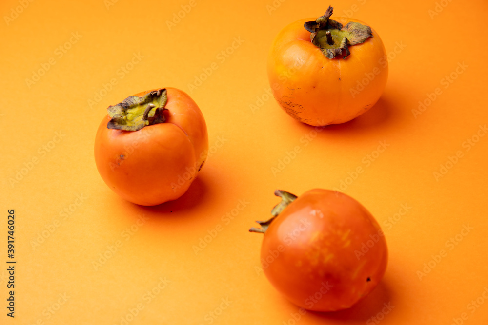 Persimmon fruit on orange background