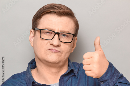 Portrait of serious proud mature man raising thumb up