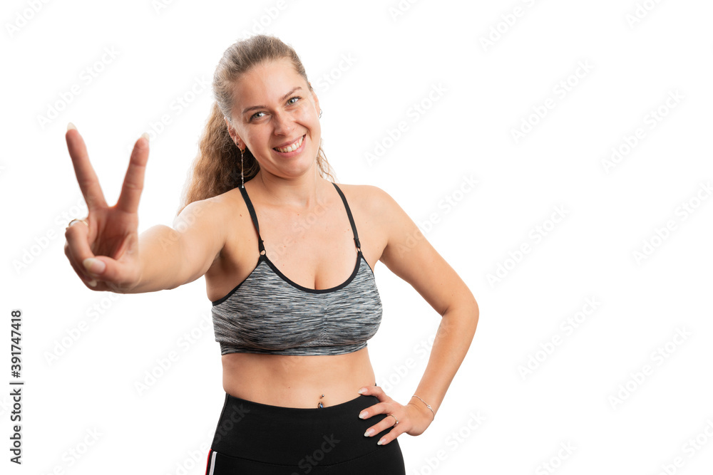 Sporty woman showing peace or victory gesture wearing gym attire Sporty woman showing peace or victory gesture wearing gym attire