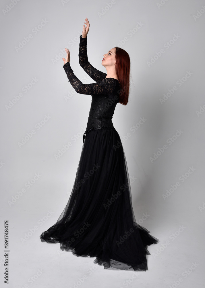 full length portrait of woman wearing black gothic dress, Standing pose against a studio background. full length portrait of woman wearing black gothic dress, Standing pose against a studio background.
