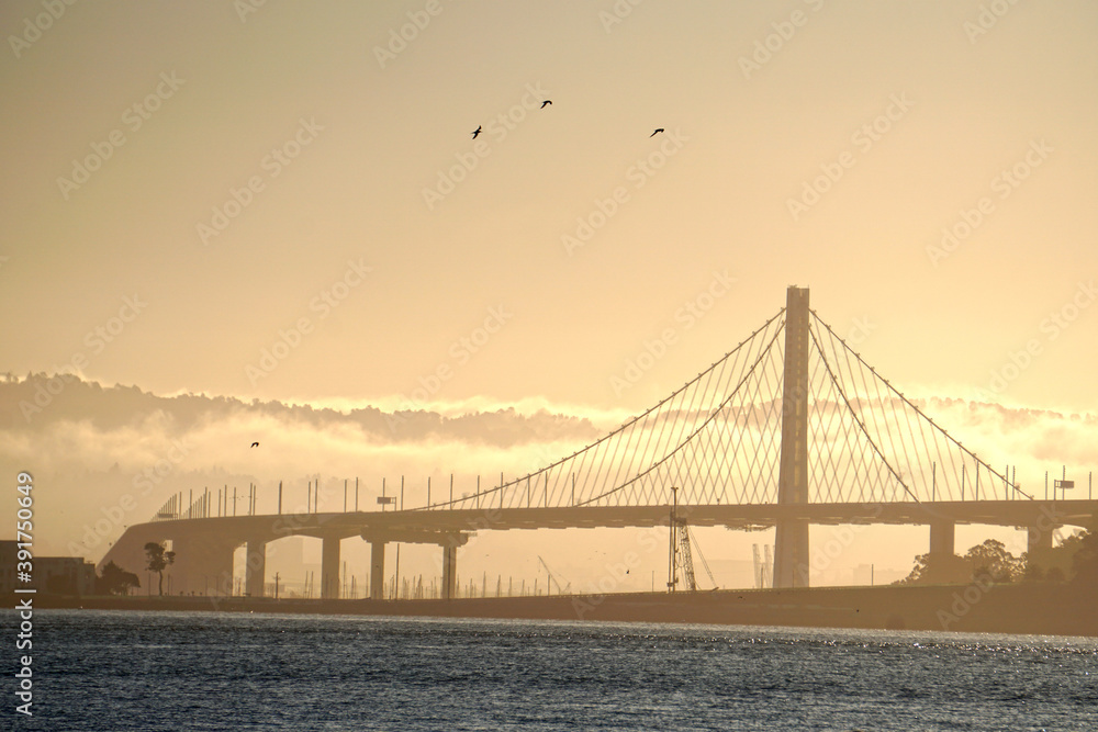 The San Francisco–Oakland Bay Bridge, locally as the Bay Bridge or as the Emperor Norton Bridge in the morning sunrise at San Francisco Bay in California USA - Infrastructure 