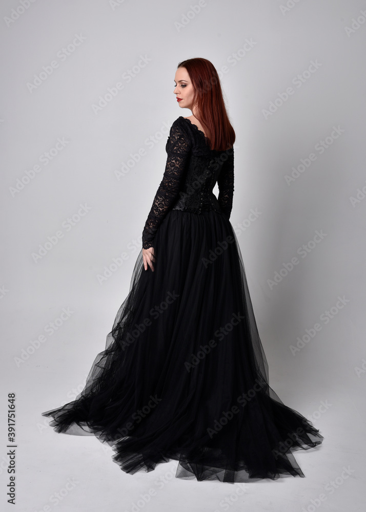 full length portrait of woman wearing black gothic dress, Standing pose against a studio background. full length portrait of woman wearing black gothic dress, Standing pose against a studio background.