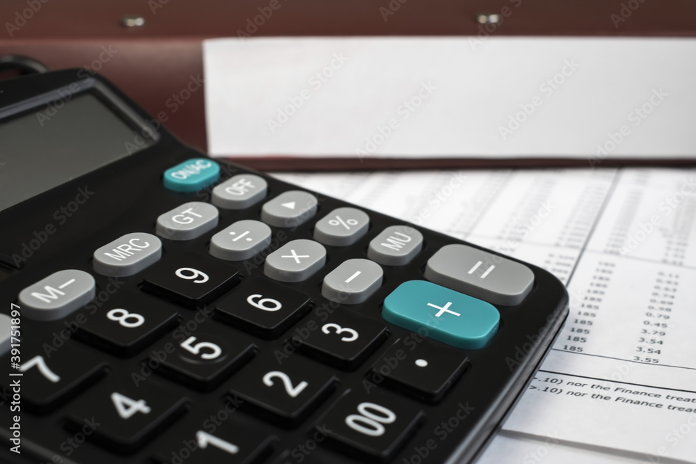 Black calculator on the blurry background of the document folder. Business concept Black calculator on the blurry background of the document folder. Business concept