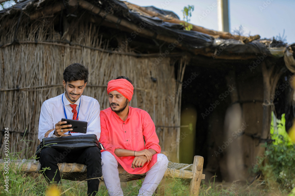 Young indian agronomist or banker showing some information to farmer in smart phone Young indian agronomist or banker showing some information to farmer in smart phone