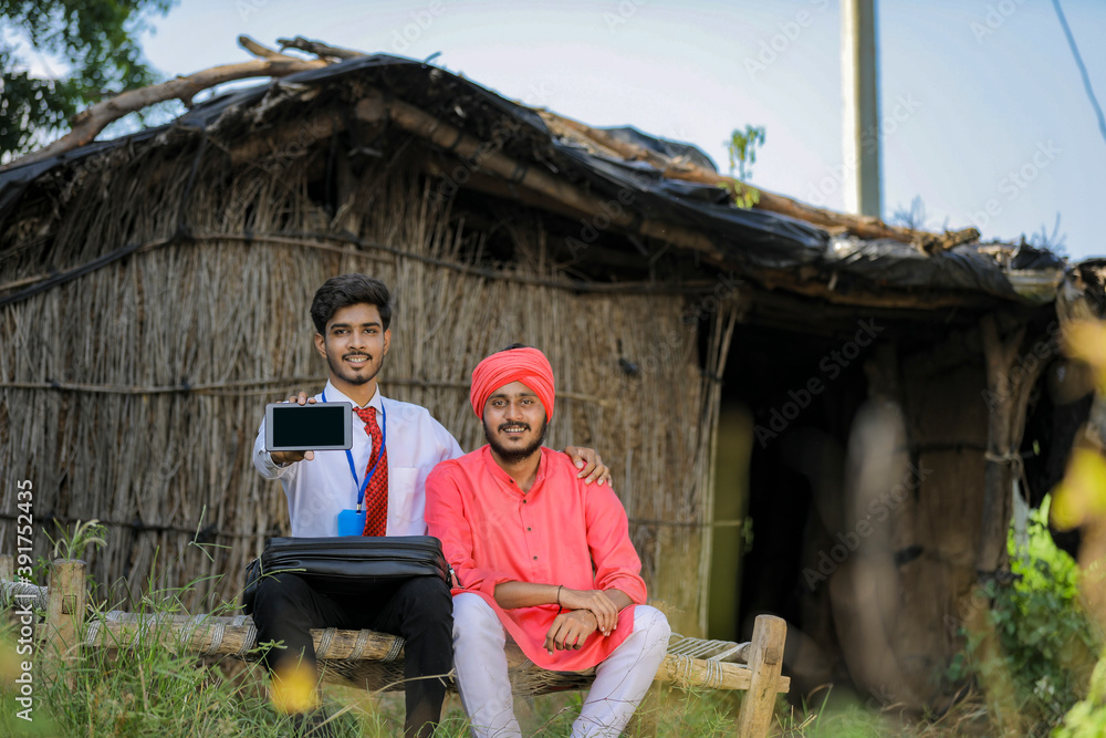 Young indian bank officer showing mobile screen with farmer Young indian bank officer showing mobile screen with farmer